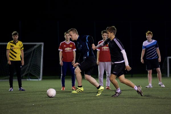 Two men chasing a ball while playing football